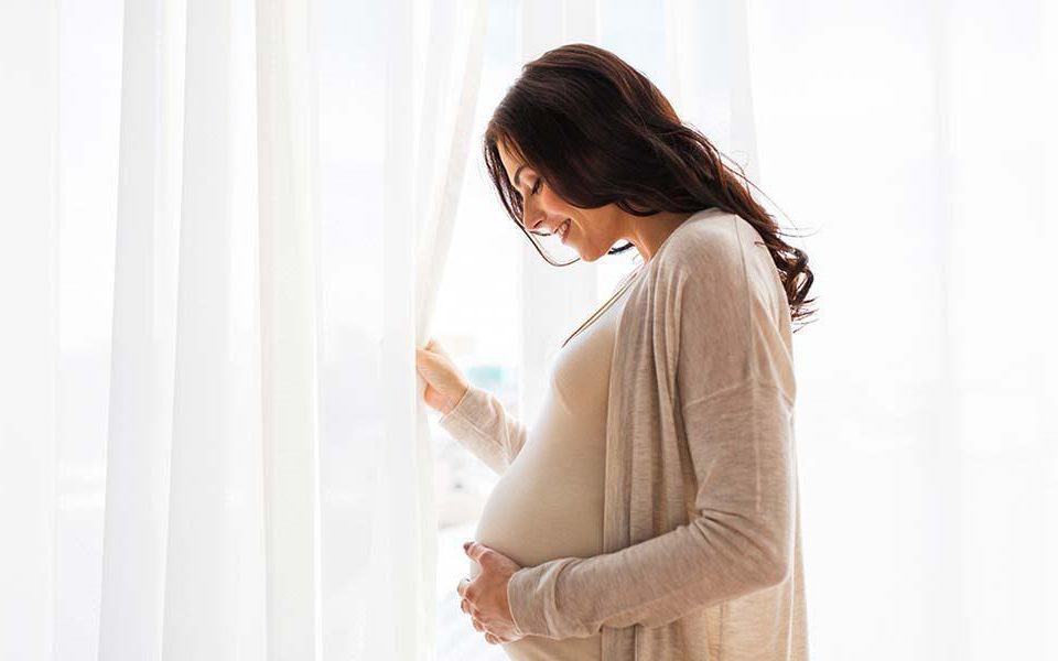 pregnant woman opening the window and smiling