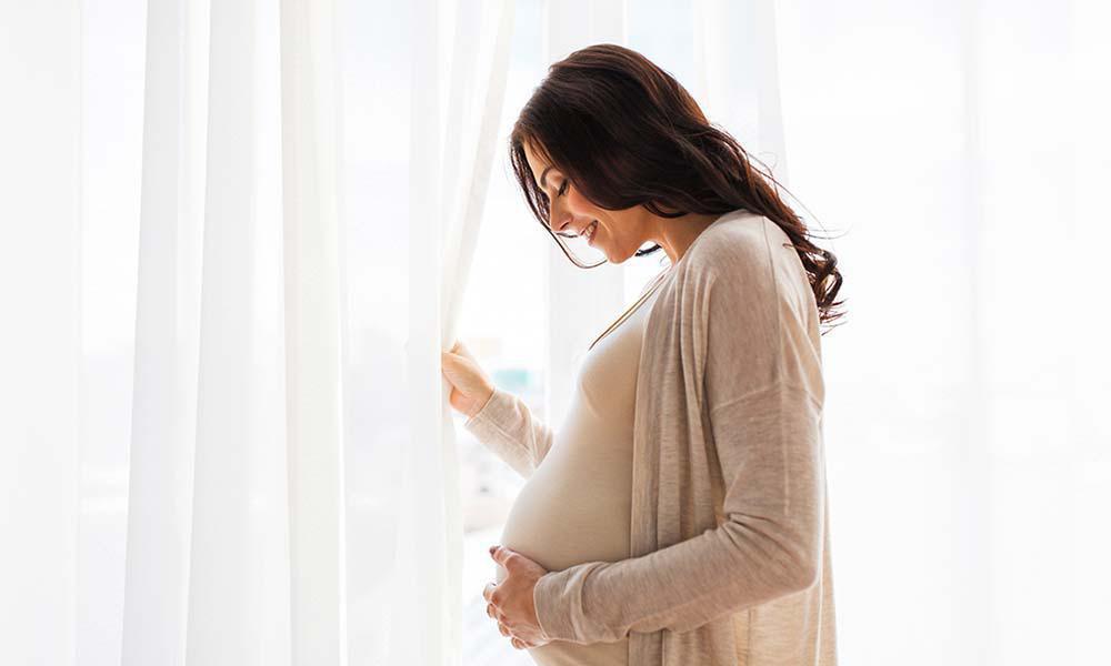pregnant woman opening the window and smiling