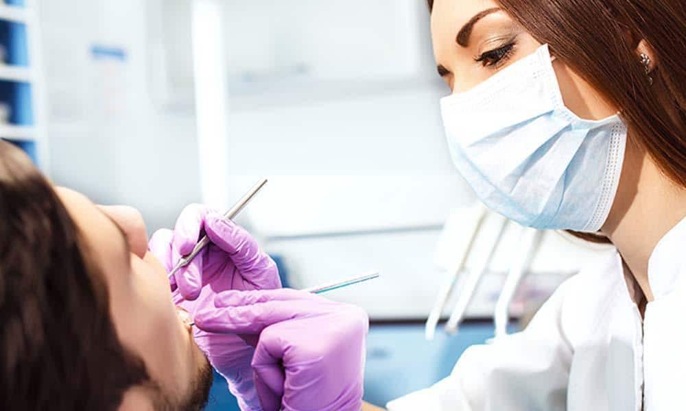 female doctor checking patient during dental exam