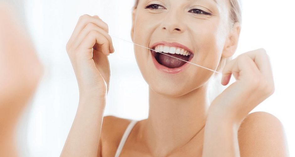 woman looking in the mirror smiling and flossing