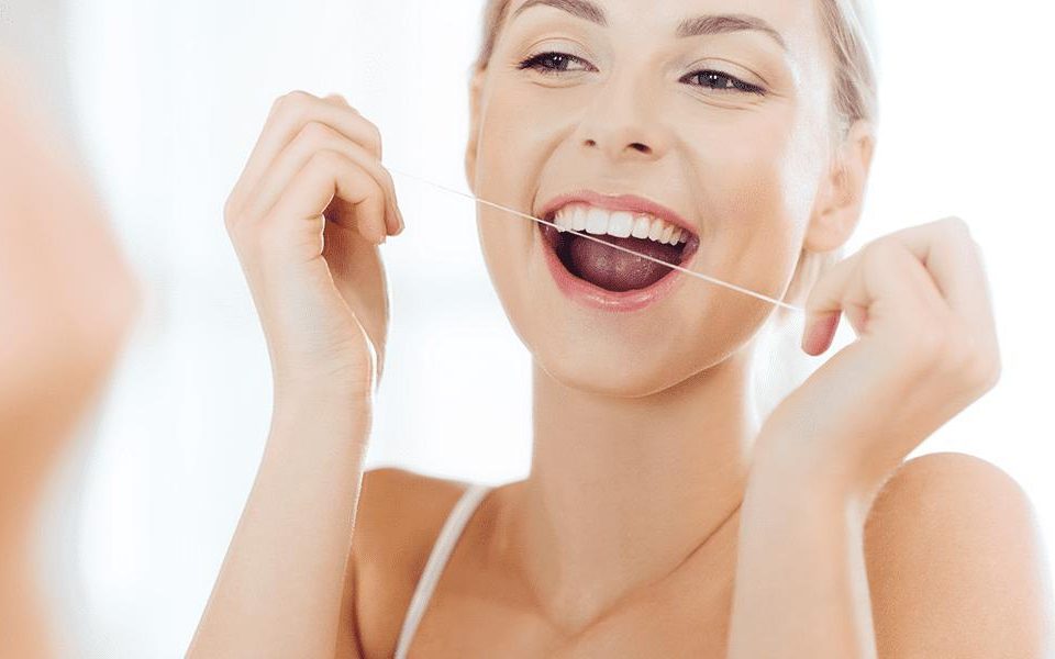 woman looking in the mirror smiling and flossing
