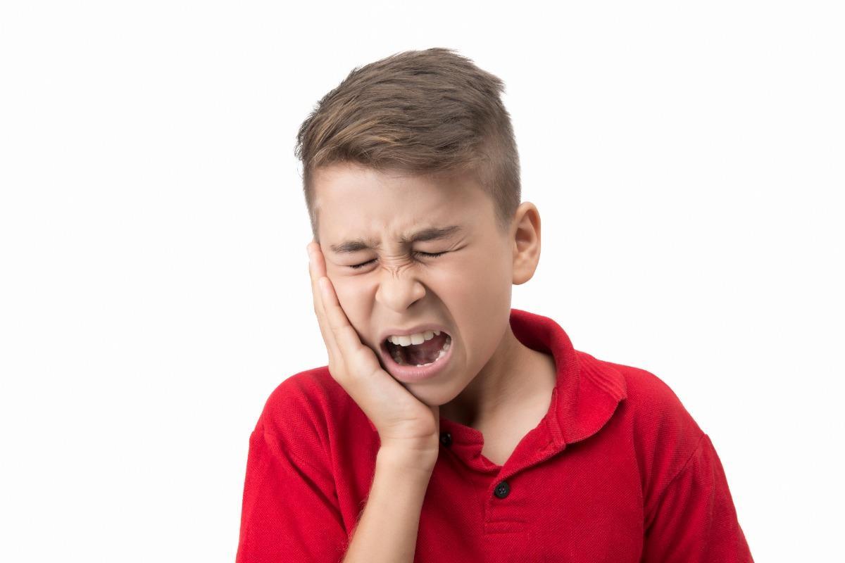 boy with hand on jaw clearly in pain