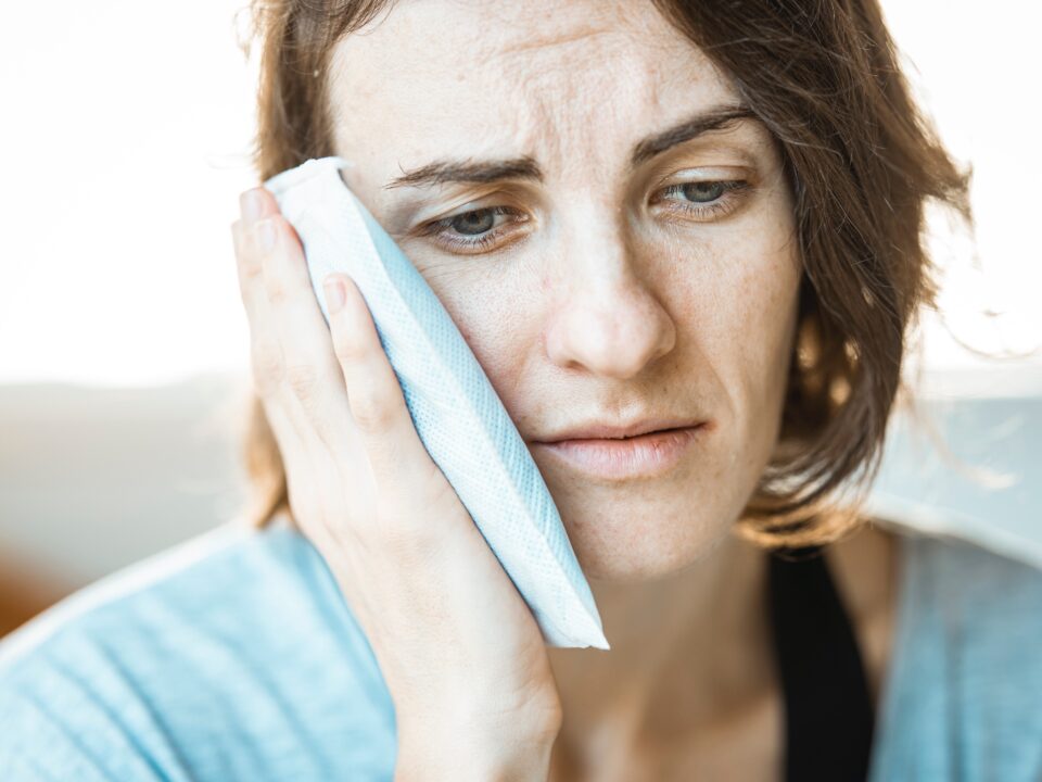 woman in visible pain holding ice pack to her jaw