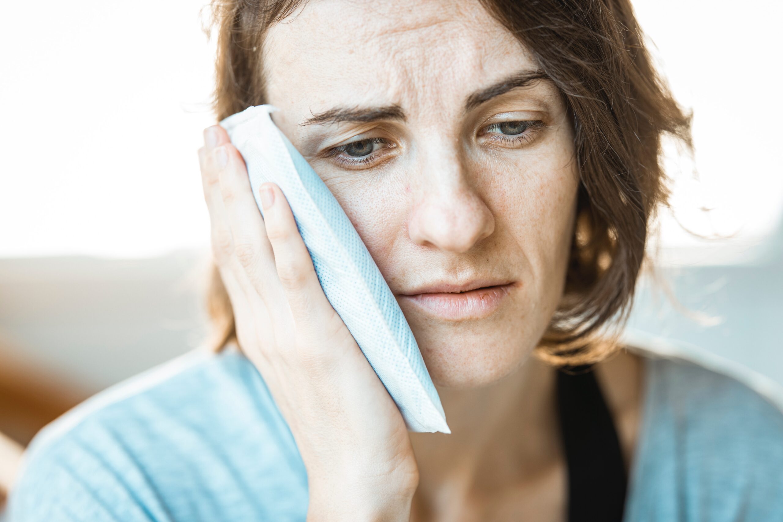 woman in visible pain holding ice pack to her jaw