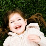 little girl laying on grass smiling