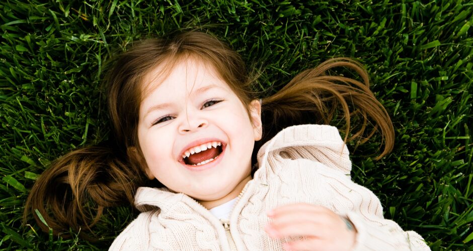 little girl laying on grass smiling