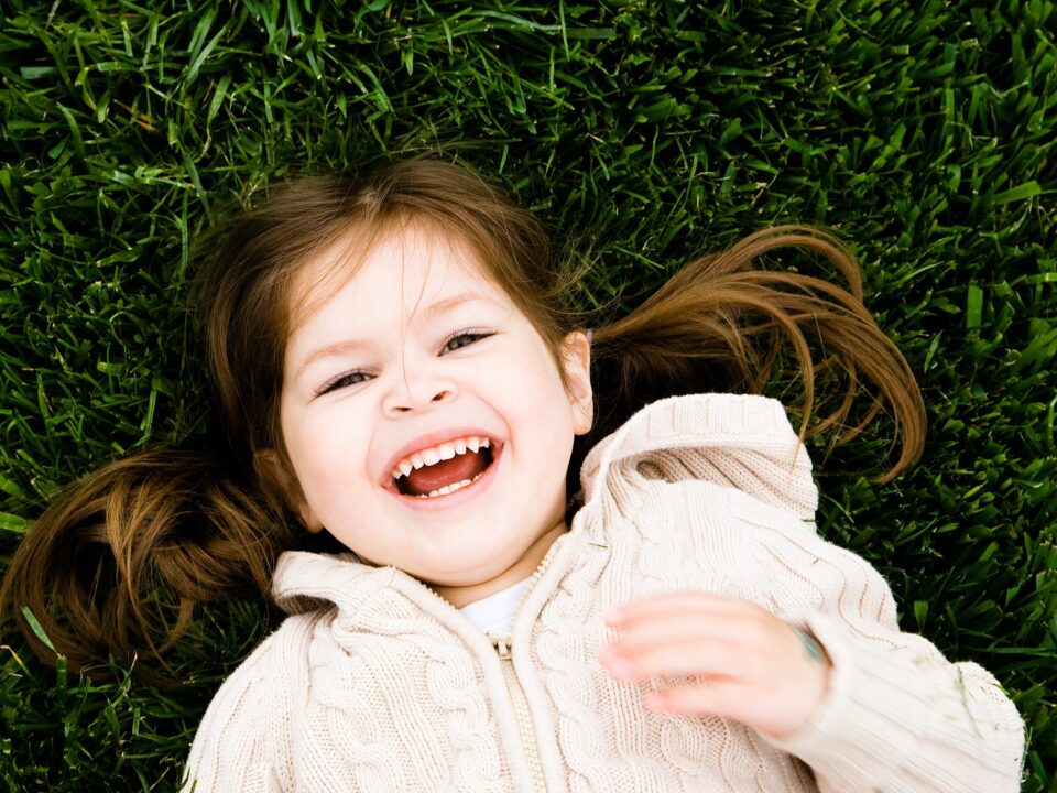 little girl laying on grass smiling